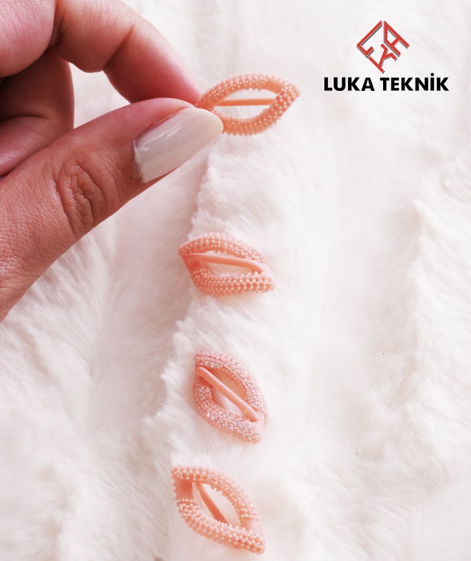 Four pink leaf-shaped jewellery pieces with beaded detail, resting on white fur